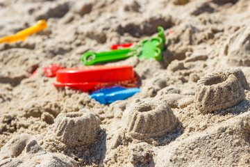 Different shapes made of sand and children toys for playing on beach. Summer, vacation time and child development