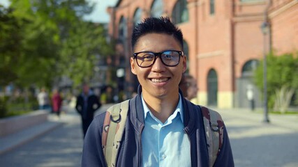 Portrait of young asian man in eyeglasses smiling and looking at camera. - Powered by Adobe