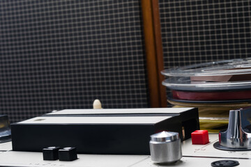 against the background of old speakers of a music magnetic player, a stack of reels with ribbons