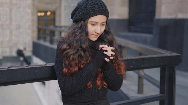Vista de una ni&ntilde;a adolescente por las calles de la Ciudad de M&eacute;xico con ropa de abrigo en una tarde de oto&ntilde;o, ni&ntilde;a se frota las manos porque tiene frio, imagen urbana con una chica recargada