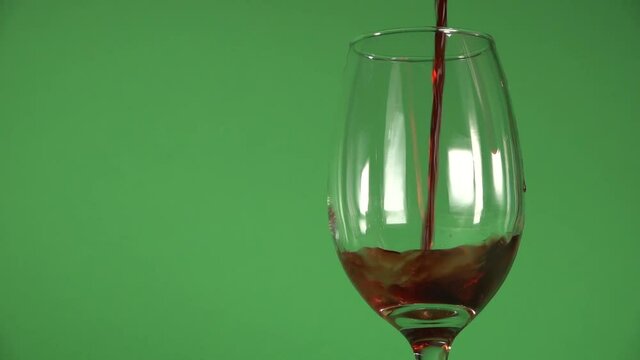 Wine being slowly poured on a glass, on a chroma background