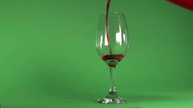 Pouring wine on a glass, in chroma background.
