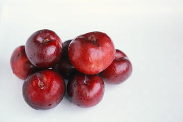 Pile of fresh juicy red plums isolated on white 
