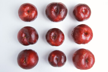 Top view of row of Fresh juicy red plums isolated on white