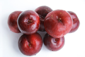 Pile of fresh juicy red plums isolated on white 