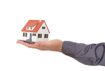 Closeup of hand holding house model in front of white background