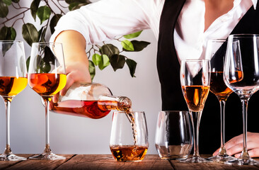Sommelier pouring rose wine into glass at wine tasting in winery, bar or restaurant. White...