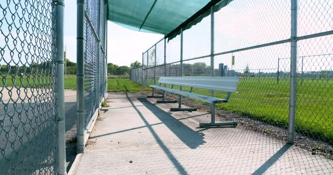 an empty bench sits in a dugout on a sunny day