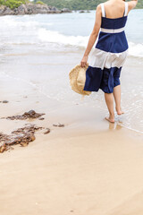 Happy young girl hold hat and walking on the beach. Summer travel, vocation, holiday concept.