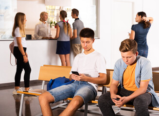 Teenage schoolers using their gadgets on break in college