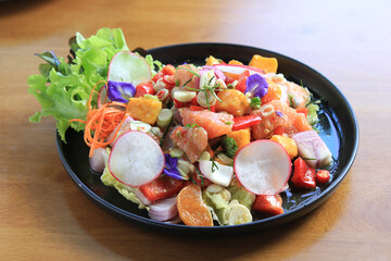 Close up smoked salmon fruit salad on natural wood table.
