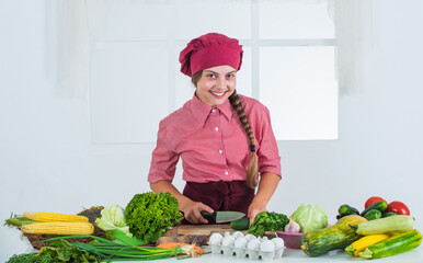 my favorite hobby. kid wear chef uniform and hat. teen girl preparing meal. fresh raw vegetables....