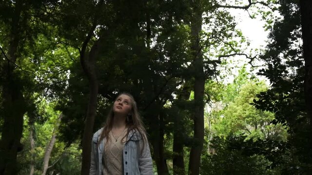 Young Caucasian female walking through woodland wilderness thinking concept slow motion