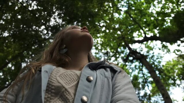 Young Caucasian female looking up at woodland tree canopy imagination expression concept