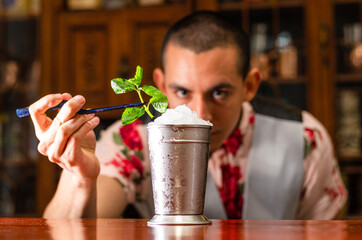 Bartender preparing delicious mint julep cocktail at table