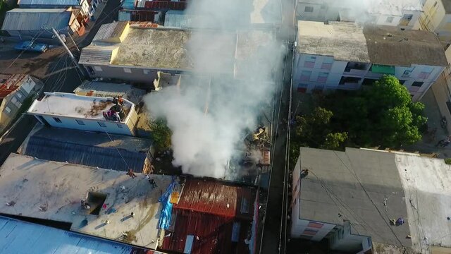 Aerial view around a smoking building fire, in poverty neighborhood Favela, Rio, Brazil, South America - orbit, drone shot