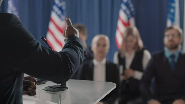 Unrecognizable African American candidate for presidency finishing his speech during debates, journalists applauding to him