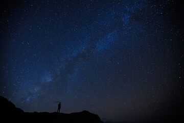 Silhouette of boy / man standing on the hill.  Stargazing at Oahu island, Hawaii. Starry night sky, Milky Way galaxy astrophotography.