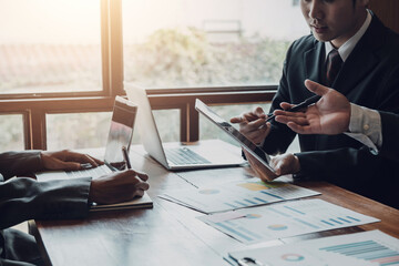 Group of business people meeting together pointing to the tablet assess business profits.