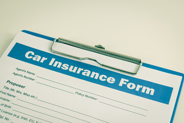 Car Insurance Claim Form or Auto Insurance Document on Right Slant and Clipboard on White Office Table in Vintage Tone