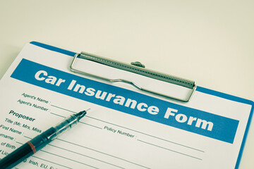 Car Insurance Claim Form or Auto Insurance Document and Pen at Left Frame and Clipboard on White Office Table in Vintage Tone