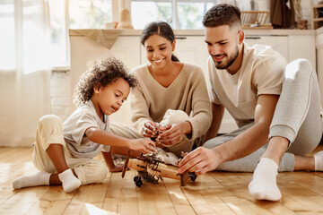 Diverse parents playing with son in kitchen.