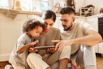happy multi ethnic family: parents and son using tablet  at home