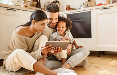 happy multi ethnic family: parents and son using tablet  at home - Powered by Adobe