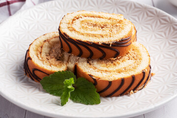 Pieces of sweet roll with cream filling on a plate and mint leaves.