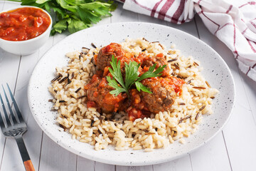 Beef meatballs and brown rice on a plate. Ready made portioned dish meat with garnish.