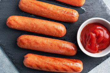 Juicy grilled meat sausages with tomato sauce and ketchup on a concrete stand. Fat fast food. Concept unhealthy eating.