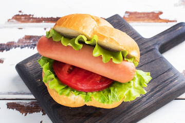 Hot dogs on a wooden Board. Hot dog with lettuce tomato and sausage. Copy space.