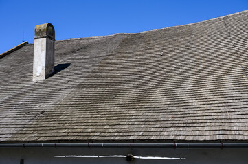 Old wooden thatched roof curved with a chimney.
