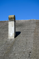 Old wooden thatched roof curved with a chimney.