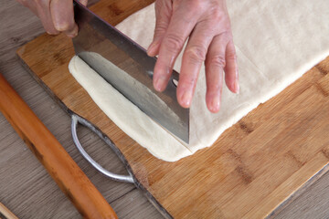 The chef cut the pie-shaped fried dough noodle into long strips with a knife