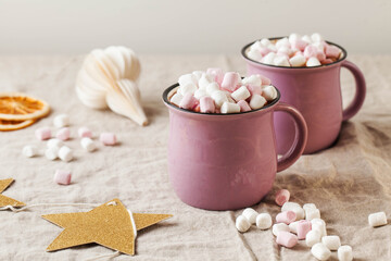 Hot chocolate with marshmallows in mugs on a linen tablecloth with Christmas toy. concept of winter home away from home