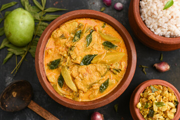 Top view of spicy hot Bengali Rohu or King fish curry. Indian food. Fish curry with red chili, curry leaf. Asian cuisine. Delicious spicy Kerala, Goan fish curry coconut milk and mangoes clay pot
