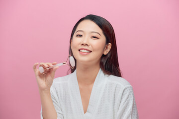 Healthy skin woman using a rose quartz face roller on her flawless skin