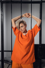 Cute blonde on a photo shoot in the prison, stays behind bars.