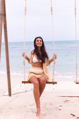 Happy smiling woman on swing at beach,day warm light. 