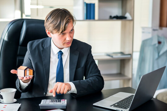 Happiness businessman hold house model in hand at office, real estate home investment or selling or financial loan concept
