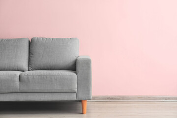 Stylish sofa near light wall in room