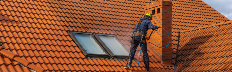  high-altitude worker washing the roof with pressurized water