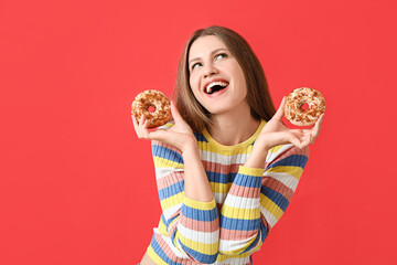 Naklejka premium Beautiful young woman with sweet donuts on color background