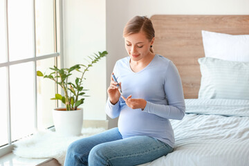 Pregnant diabetic woman measuring blood sugar level at home