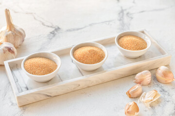Bowls with aromatic powdered garlic on white background