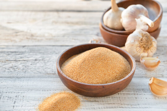 Plate with aromatic powdered garlic on table