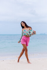 Happy woman with long hair in pink shorts enjoy time on beach by sea  