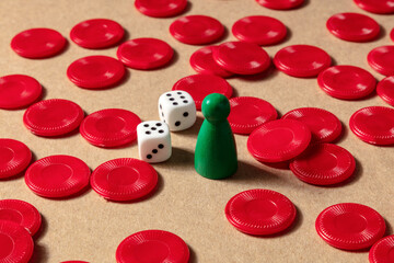 Board games concept. Red pieces, dice, and a pawn on a brown background
