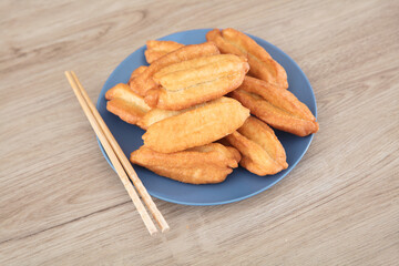 A plate of fried dough sticks and a pair of chopsticks on the table